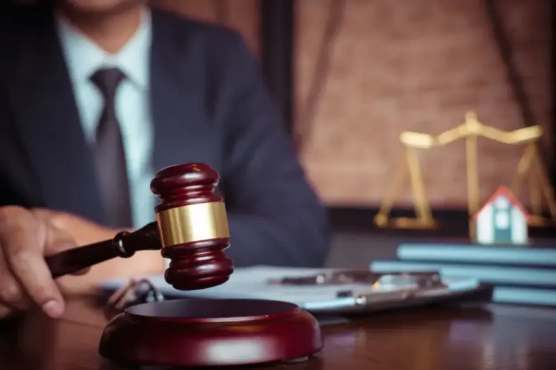 Judge holds a gavel over the desk, with the scales of justice in the background