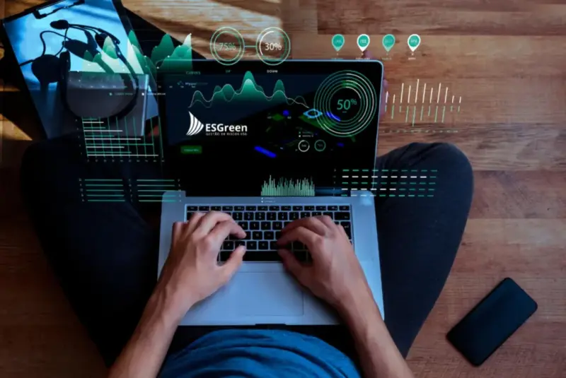 Person uses a laptop with an ESGreen dashboard showing monitoring indicators